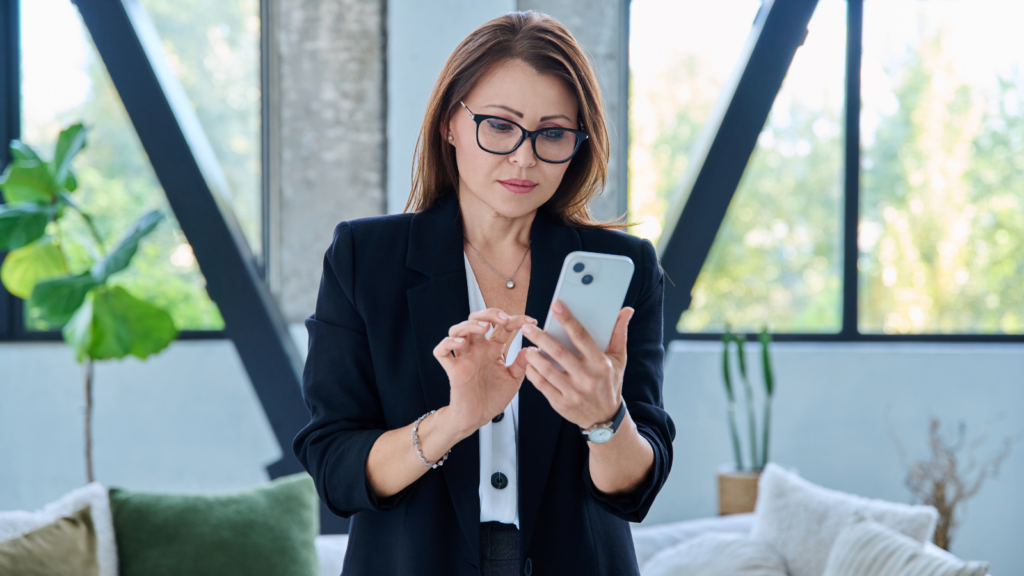Woman in a black blazer using a smartphone in an office
